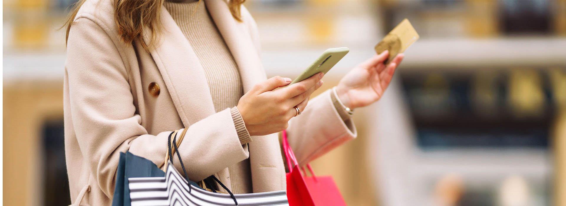 Woman wearing a coat holding value card in one hand and cell phone in the other