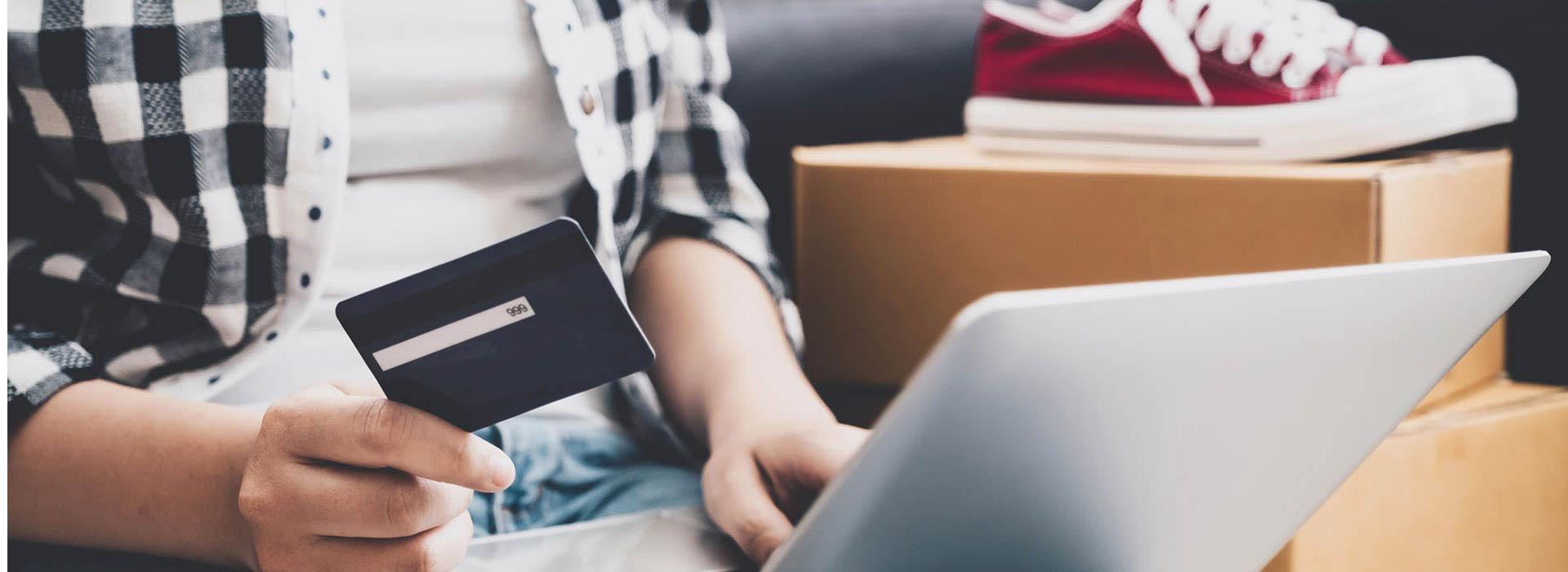 male teenager making red sneakers purchase with credit card and laptop