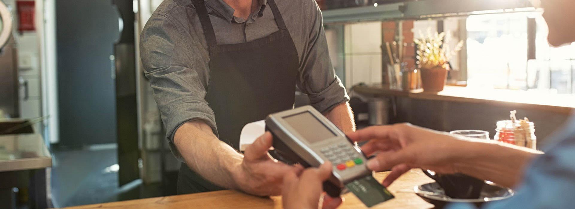 male barista taking credit card payment from female customer