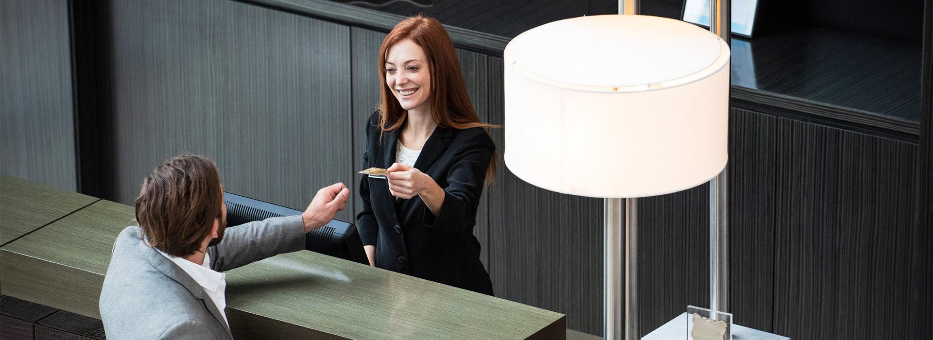 woman at hotel giving her credit card to the front desk attendant