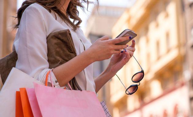 woman walking holding shopping bags and sunglasses